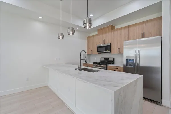 a kitchen with a refrigerator a sink and a stove top oven with wooden floor