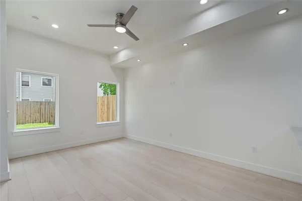 an empty room with windows and fan