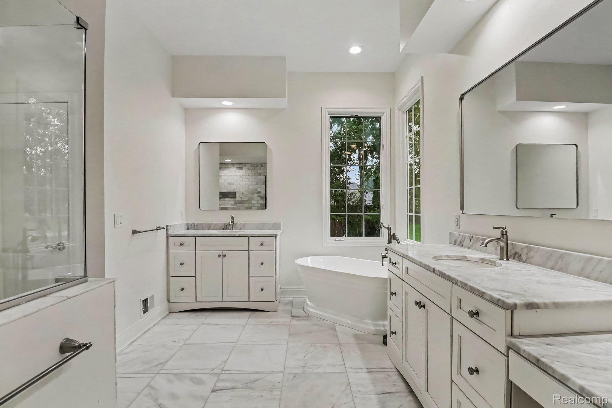 4875 Green Meadow Lane Rochester, MI 48306 - Photo 36 of 60 Spacious bathroom featuring a freestanding tub, dual vanity with stone countertops, tiled flooring, and a glass-enclosed shower
