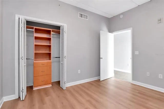 a view of an empty room with closet and wooden floor