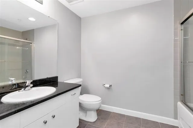 a bathroom with a granite countertop sink a toilet and a mirror