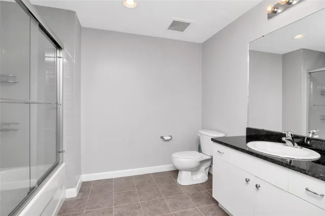 a bathroom with a granite countertop sink a toilet and a shower