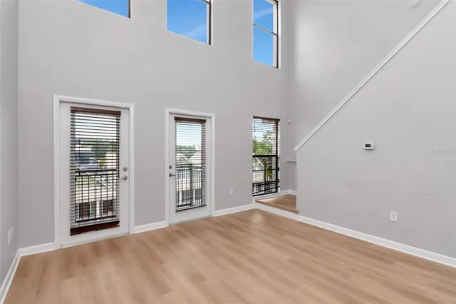 a view of an empty room with wooden floor and windows