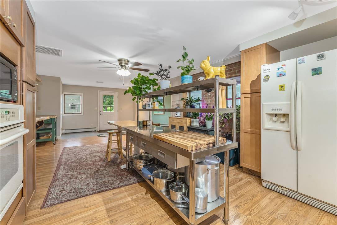4831 Steuben Road Nazareth, PA 18064 - Photo 7 of 34 An open-concept kitchen features a large stainless steel island with ample storage and a wood countertop, complemented by light wood flooring and a classic ceiling fan.