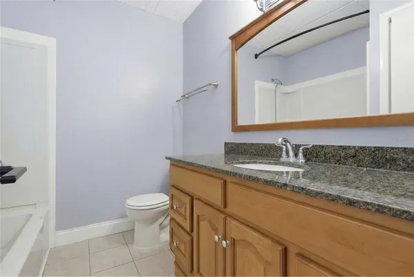 a bathroom with a granite countertop sink a toilet and a mirror