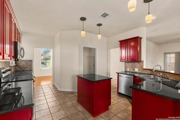 a kitchen with granite countertop a sink a counter space appliances and cabinets