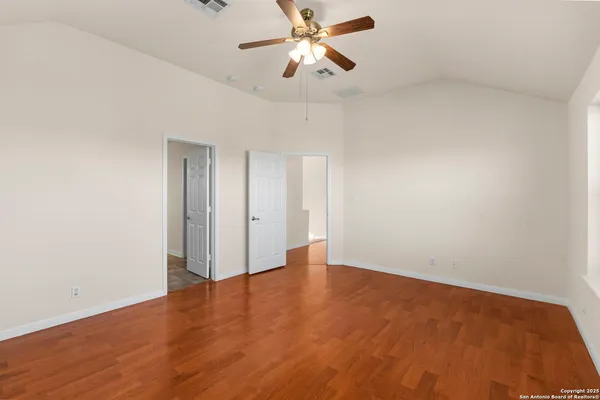 a view of an empty room and chandelier fan