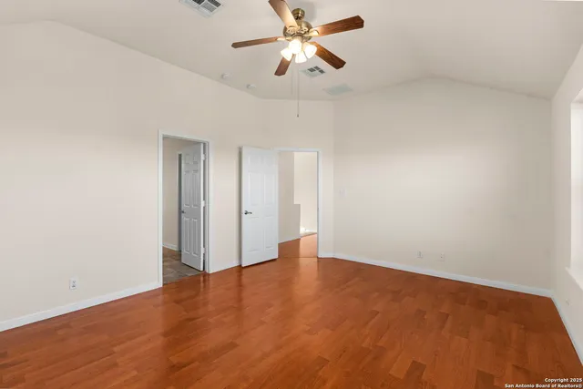 a view of an empty room and chandelier fan