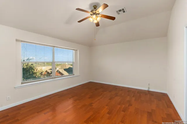 an empty room with windows and fan