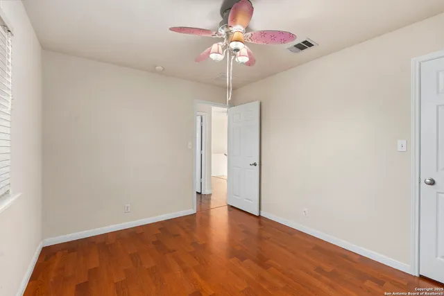 a view of an empty room with window and chandelier fan