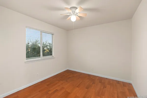 an empty room with a window and a fan