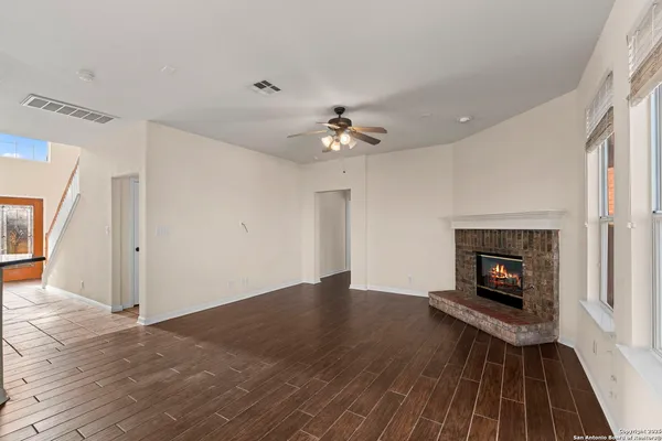 a view of a livingroom with a fireplace a ceiling fan and wooden floor