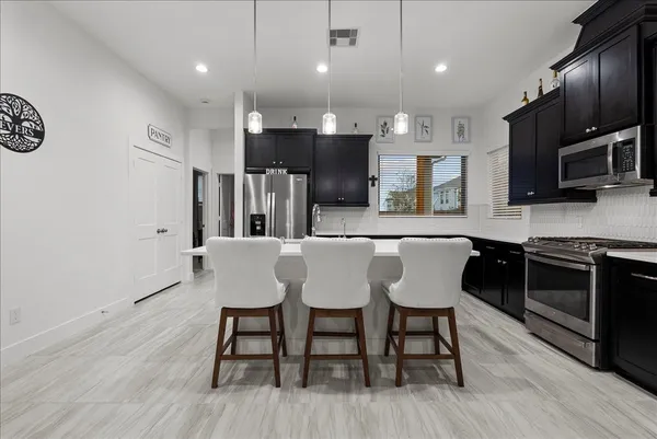 a large kitchen with stainless steel appliances kitchen island granite countertop a large stove a sink dishwasher and a refrigerator with wooden floor