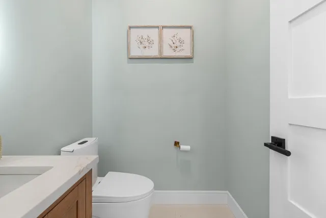 a white toilet sitting next to a white sink and vanity