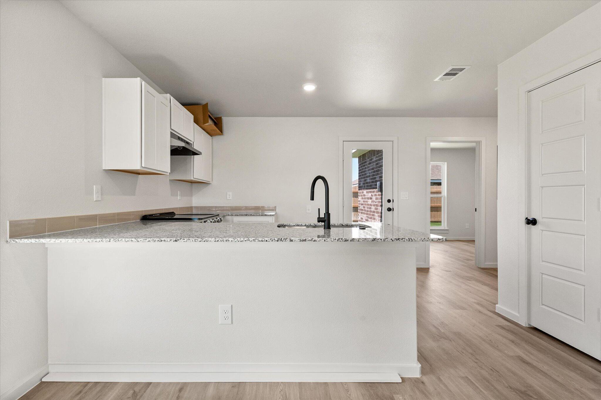 8312 25th Street Lubbock, TX 79407 - Photo 8 of 17 a view of a kitchen with kitchen island a sink wooden floor and stainless steel appliances