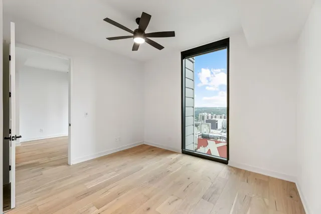 an empty room with wooden floor fan and windows