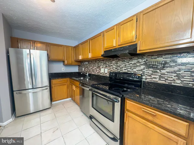 a kitchen with stainless steel appliances granite countertop a stove a refrigerator and a sink