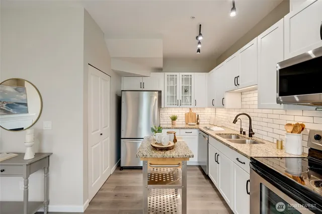 a kitchen with stainless steel appliances granite countertop a sink refrigerator stove and microwave