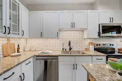 a kitchen with stainless steel appliances granite countertop a sink stove and cabinets