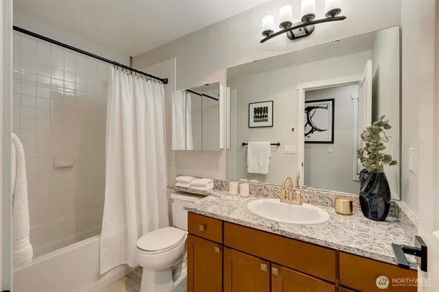 a bathroom with a granite countertop sink toilet and shower