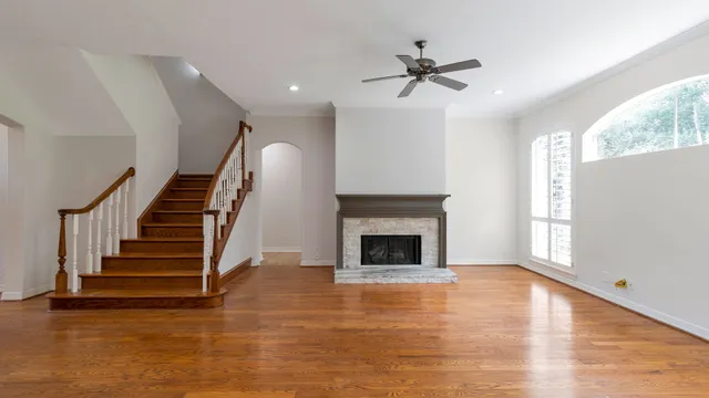 a view of an empty room with wooden floor fireplace and a window