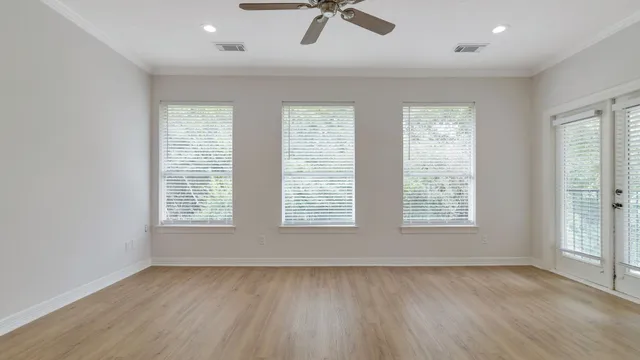 a view of an empty room with a window and wooden floor