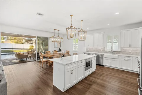 a large white kitchen with a large window a sink stainless steel appliances and cabinets