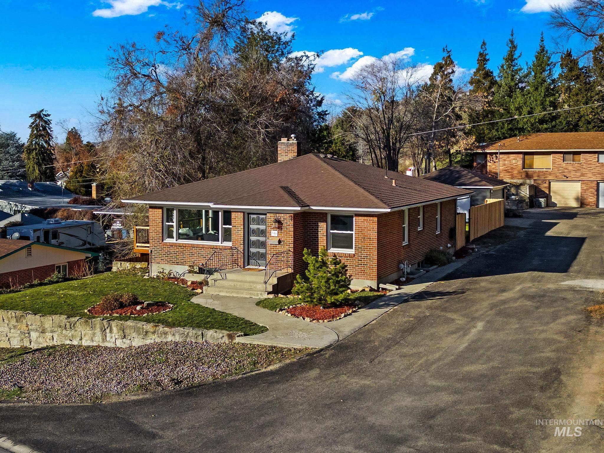 300 West Ofarrell Street Boise, ID 83702 - Photo 12 of 50 View of front of property featuring a chimney, brick siding, a shingled roof, asphalt driveway, and a front lawn