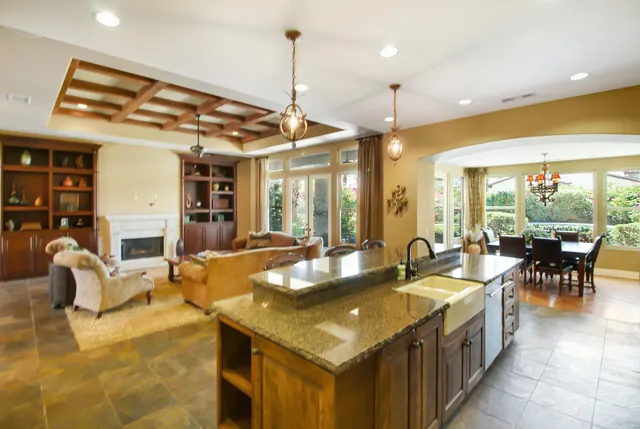 a dining hall with stainless steel appliances granite countertop a sink counter space and living room view