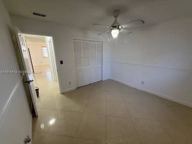 a view of a room with a ceiling fan and window