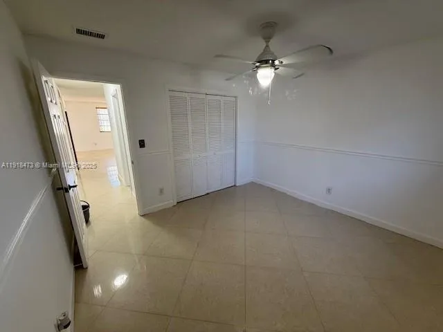 a view of a room with a ceiling fan and window