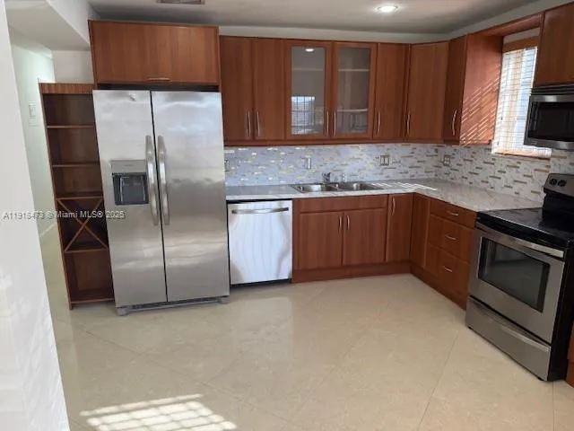 a kitchen with stainless steel appliances granite countertop a refrigerator and a sink