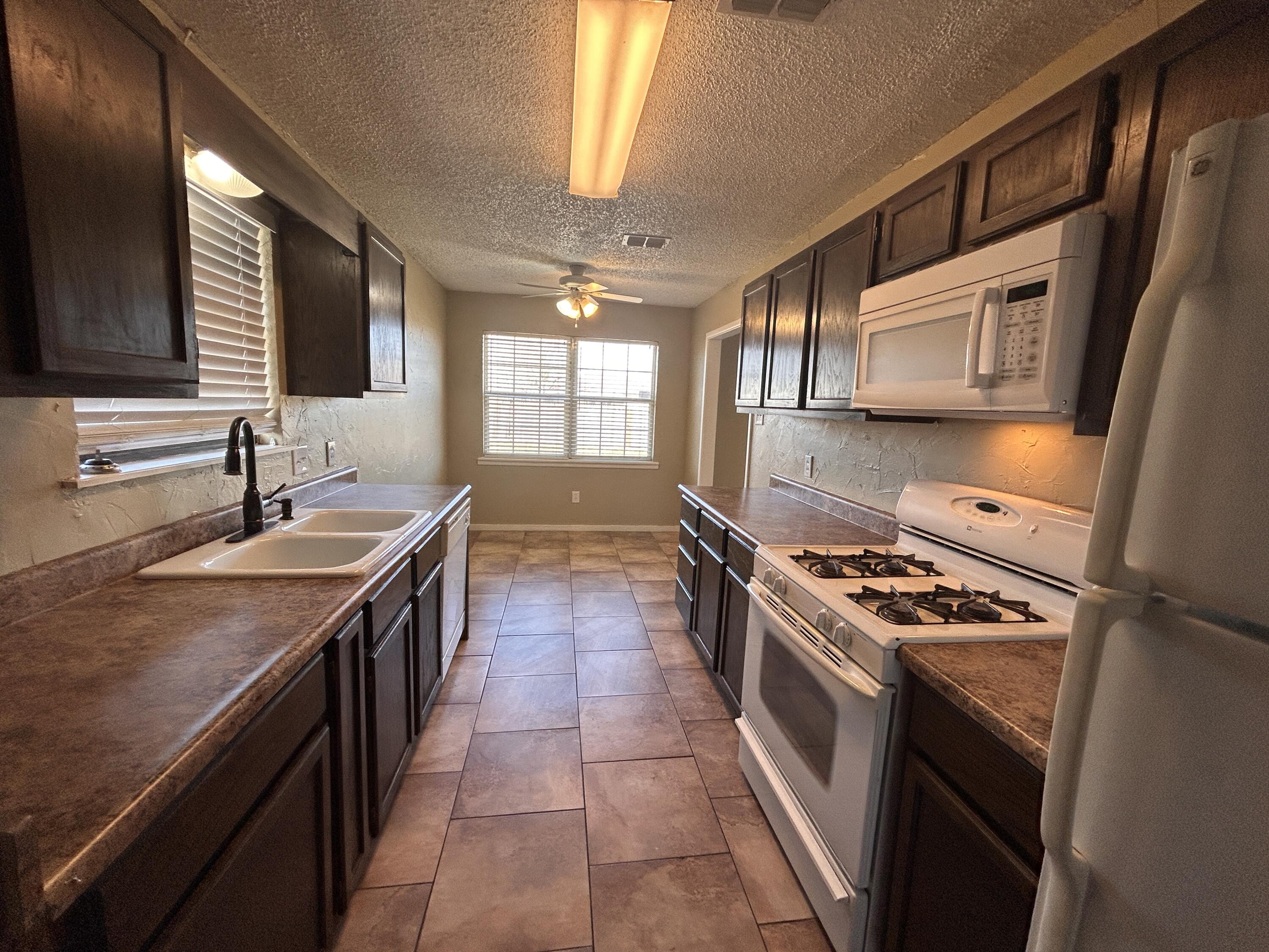 6508 25th Street Lubbock, TX 79407 - Photo 6 of 14 a kitchen with a stove sink and cabinets