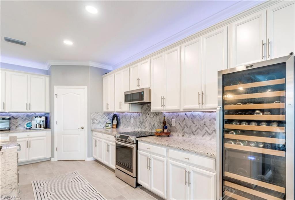 19812 Beechcrest Place Estero, FL 33928 - Photo 11 of 50 a kitchen with stainless steel appliances a stove sink and cabinets