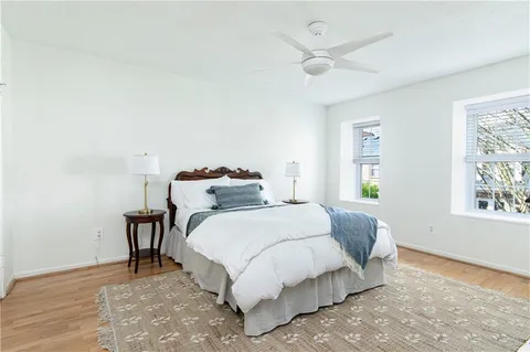 a bedroom with a bed and a large window with wooden floor