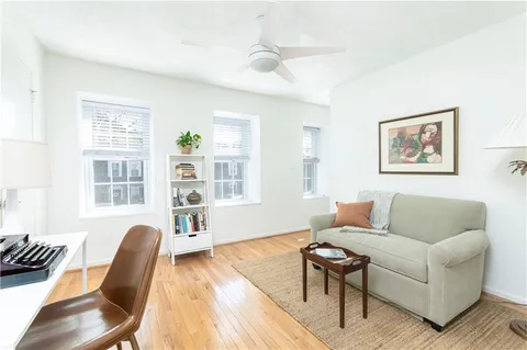 a living room with furniture two window and wooden floor