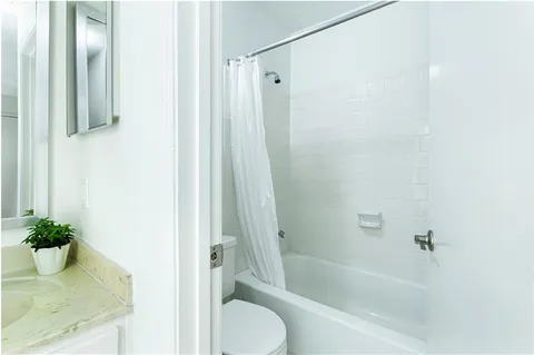 a bathroom with a granite countertop bathtub shower and toilet