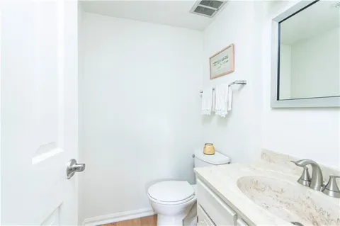 a bathroom with a granite countertop sink and a toilet