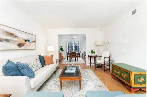 a living room with furniture and a dining table with wooden floor