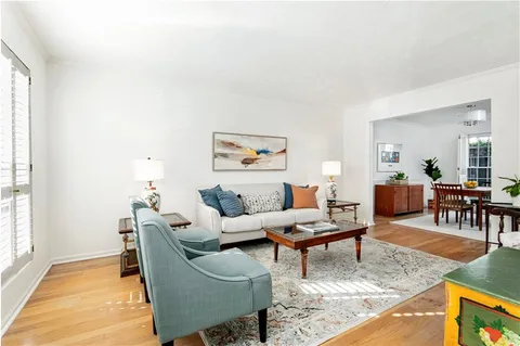 a living room with furniture and a dining table with wooden floor
