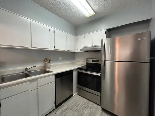 a kitchen with stainless steel appliances granite countertop a refrigerator sink and cabinets
