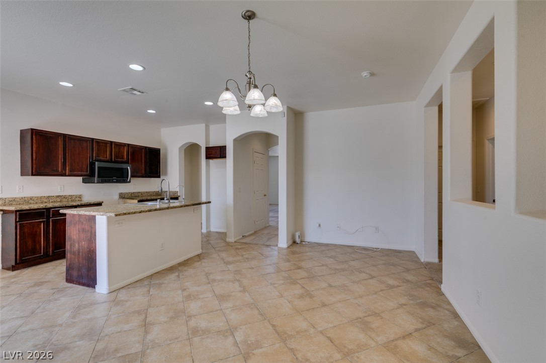 5150 Riverside Run Court North Las Vegas, NV 89081 - Photo 22 of 50 An open concept kitchen features warm cabinetry, granite countertops, and tile flooring, perfect for gatherings.