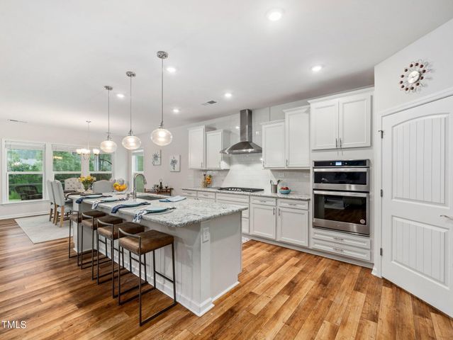a kitchen with stainless steel appliances granite countertop a sink a stove and a white cabinets