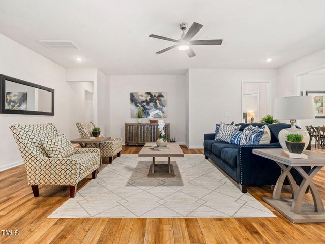 a living room with furniture kitchen view and a wooden floor