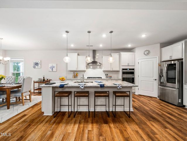 a kitchen with kitchen island granite countertop a sink a stove a dining table and chairs
