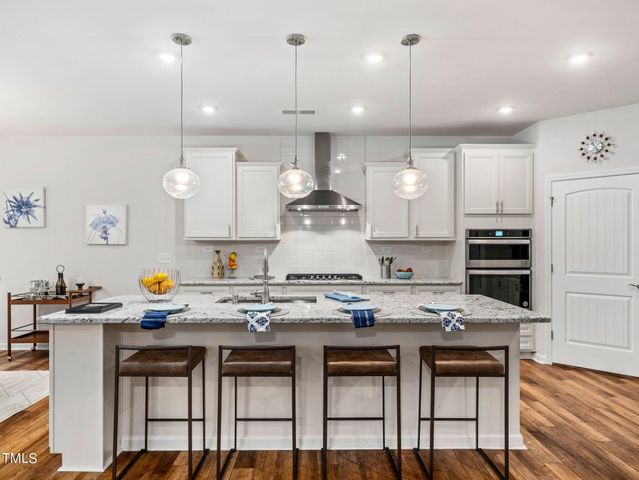 a kitchen with a sink a stove cabinets and wooden floor