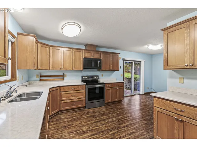 a kitchen with granite countertop a sink cabinets and stainless steel appliances