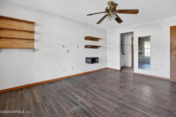 a view of empty room with wooden floor and fan