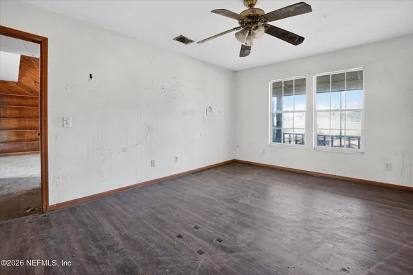 a view of an empty room with a window and wooden floor