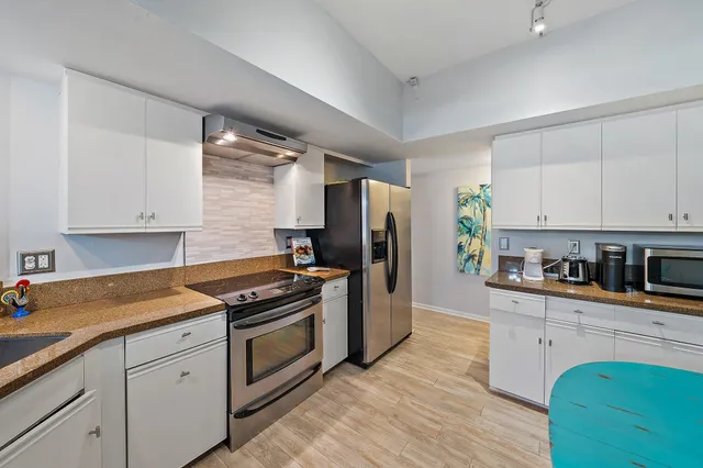 a kitchen with cabinets stainless steel appliances and wooden floor